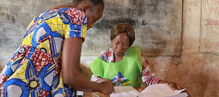 An electoral officer (right) assists a voter at a polling station during run-off presidential elections in the Central African Republic.